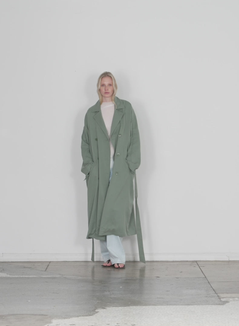 Model wearing the lancaster lyocell trench sage green walking forward and turning around