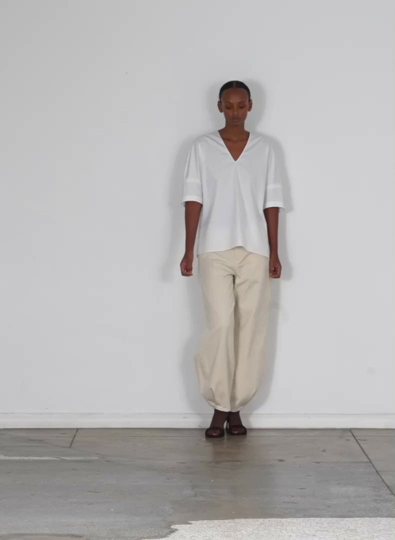 Model wearing the eco poplin vneck cocoon top white walking forward and turning around