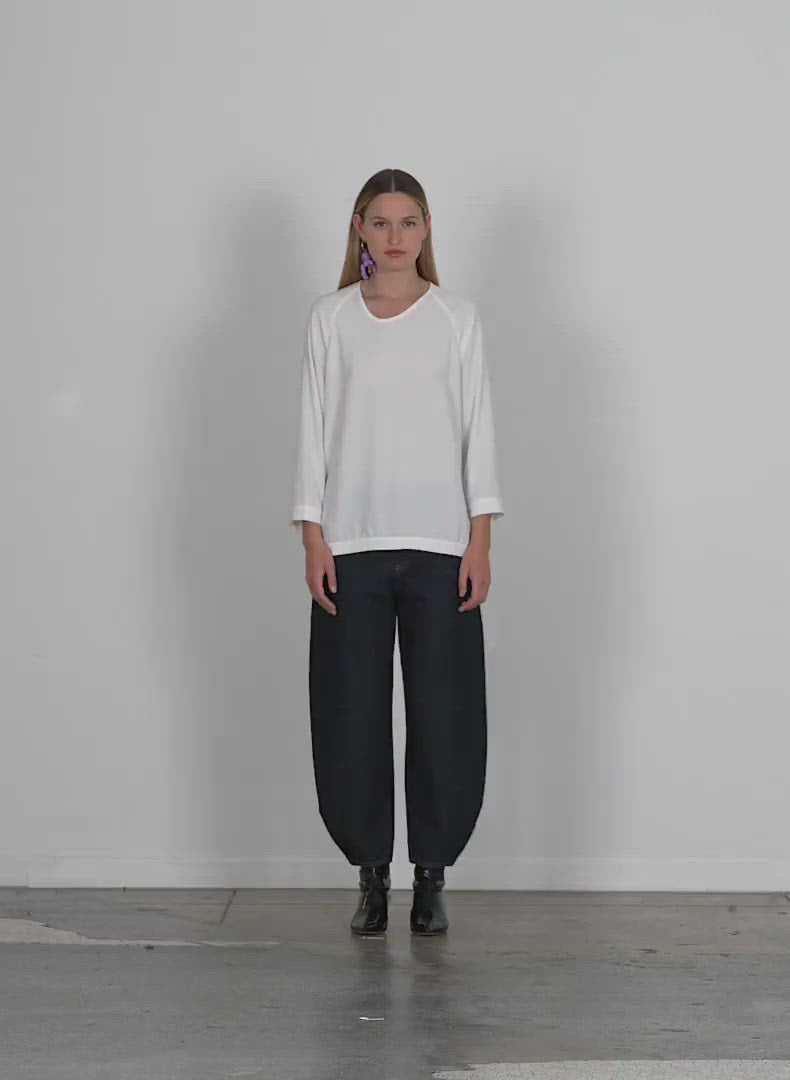 Model wearing the soft drape asymmetrical sweatshirt walking forward and turning around