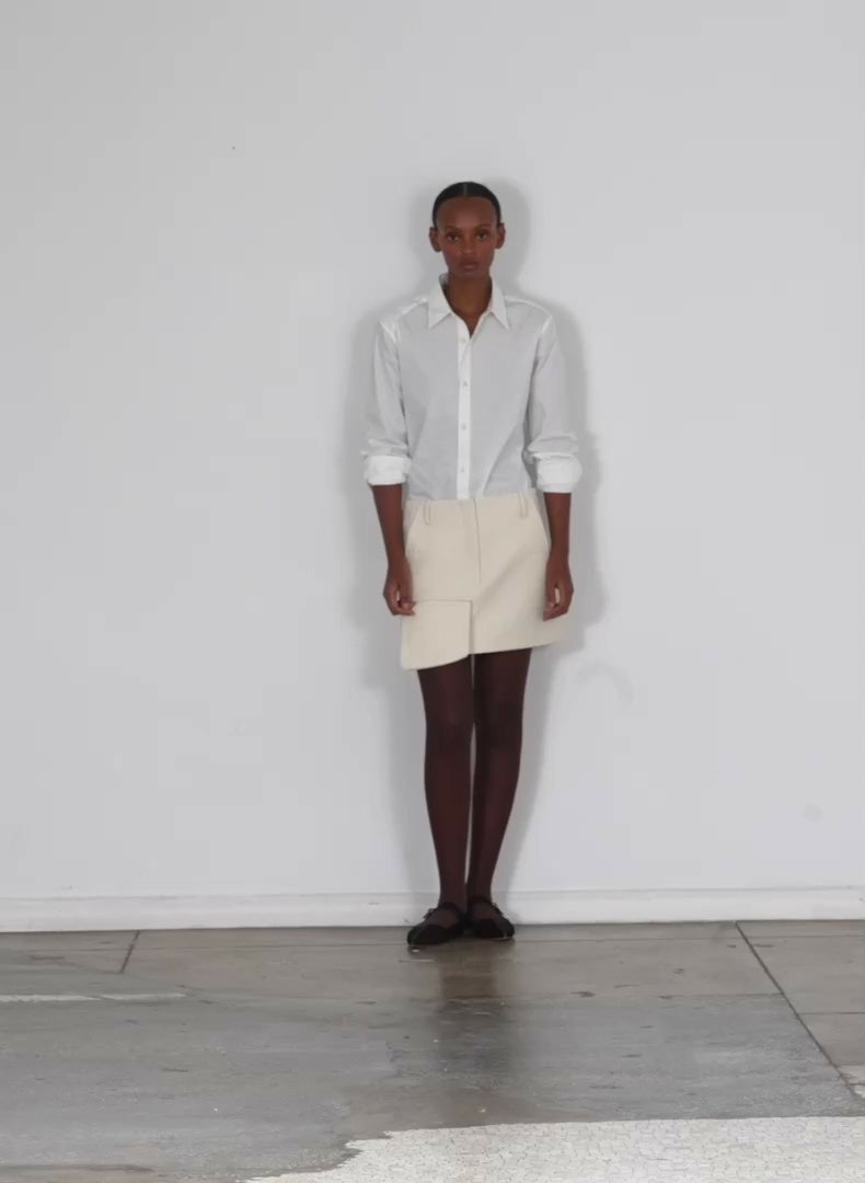 Model wearing the boiled wool mini skirt ivory walking forward and turning around