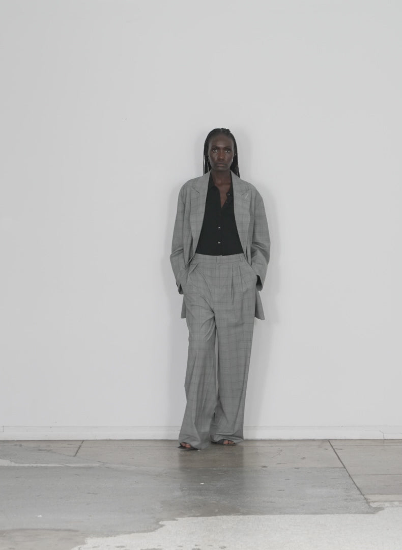 Model wearing the menswear suiting asymmetrical pleat stella pant white black mul walking forward and turning around