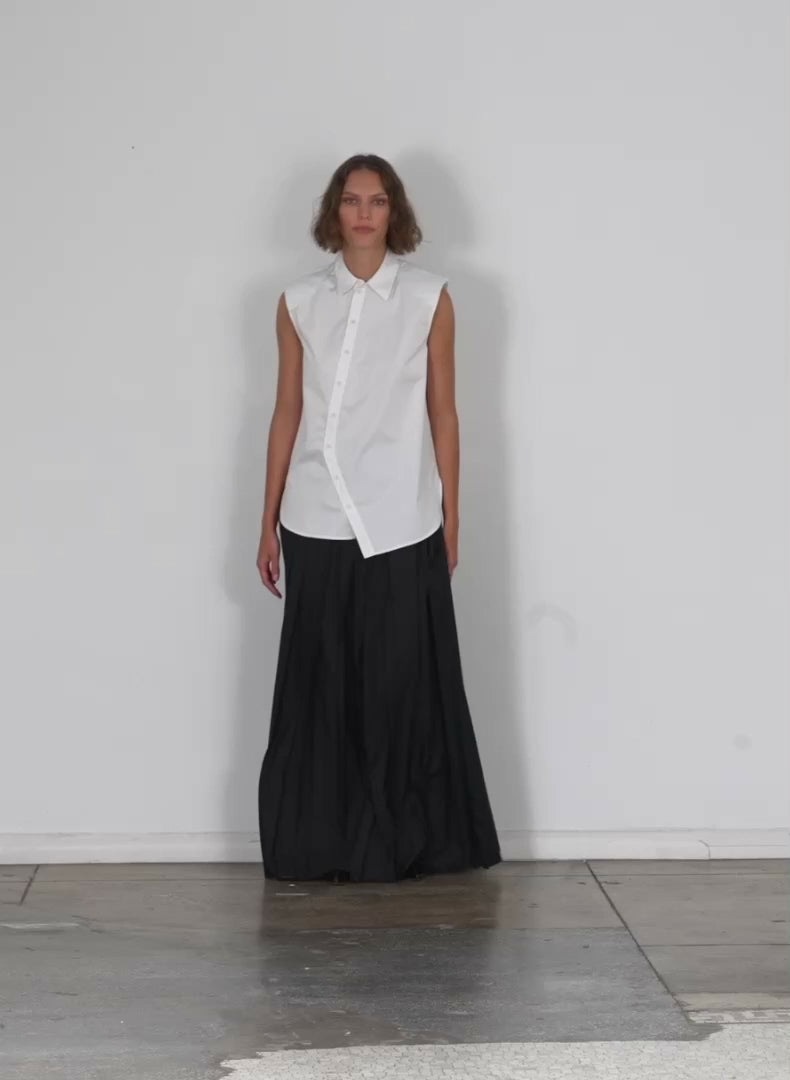 Model wearing the eco poplin sleeveless shoulderpad shirt white walking forward and turning around