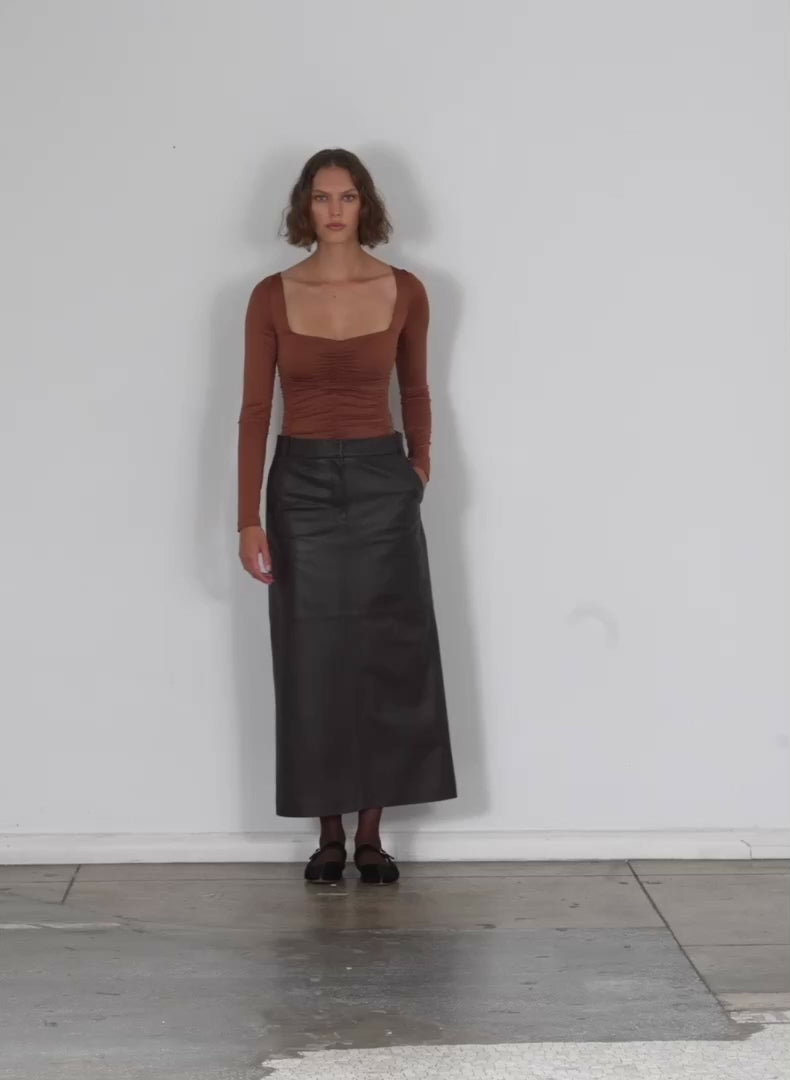 Model wearing the leather maxi trouser skirt brown walking forward and turning around