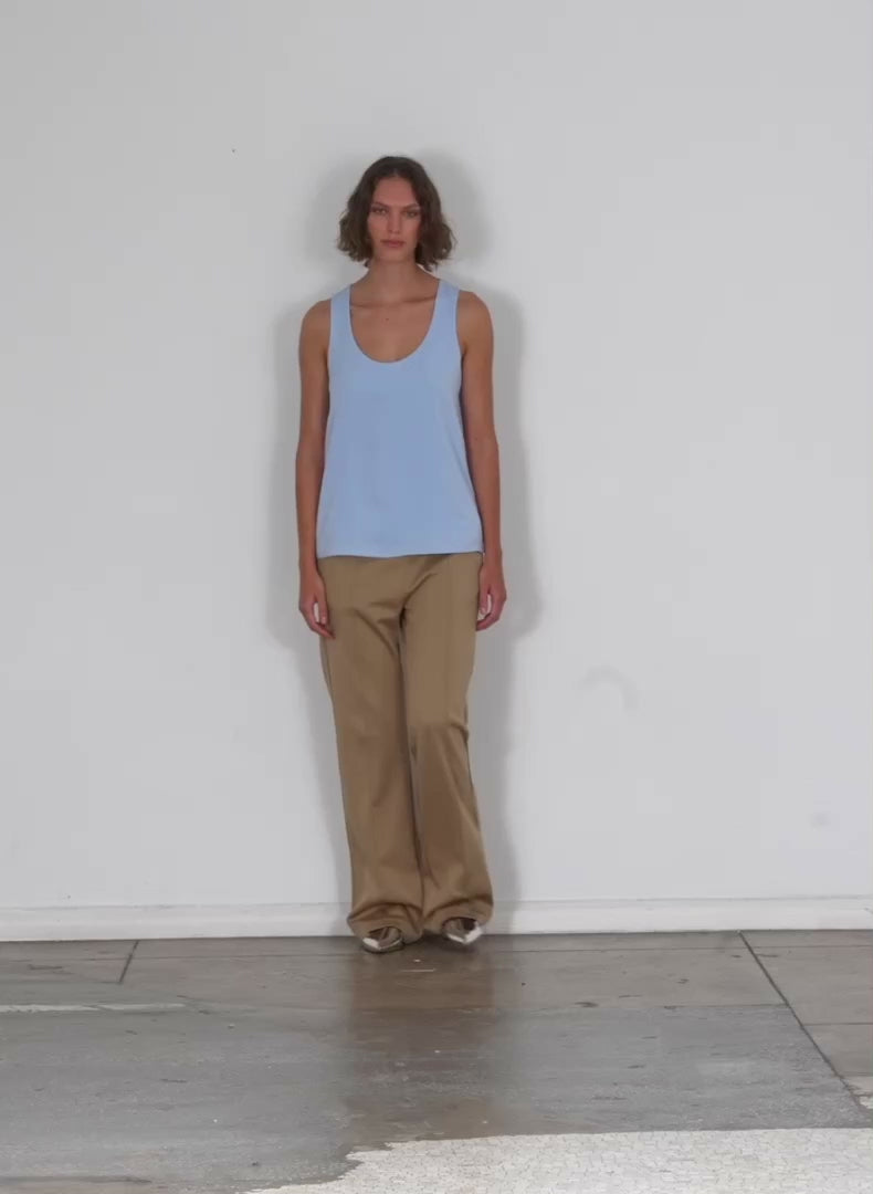 Model wearing the soft drape tank light blue walking forward and turning around