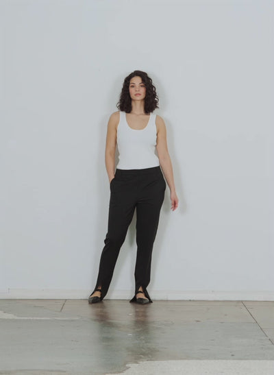 Model wearing the cassius suiting slim pant with front slit detail black walking forward and turning around