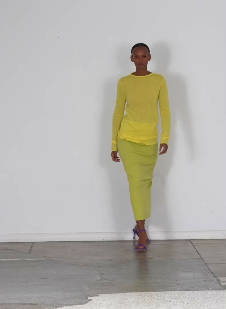 Model wearing the skinlike mercerized wool soft sheer pullover yellow walking forward and turning around