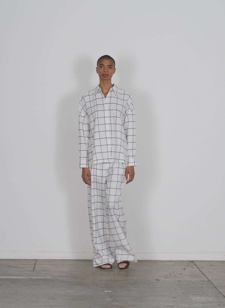 Model wearing the windowpane techy twill gabe oversized shirt white black multi walking forward and turning around