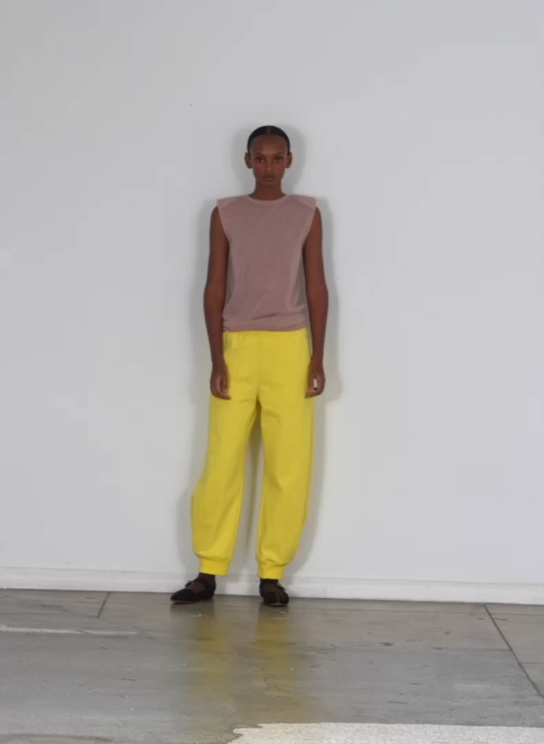 Model wearing the calder sweatpant yellow walking forward and turning around
