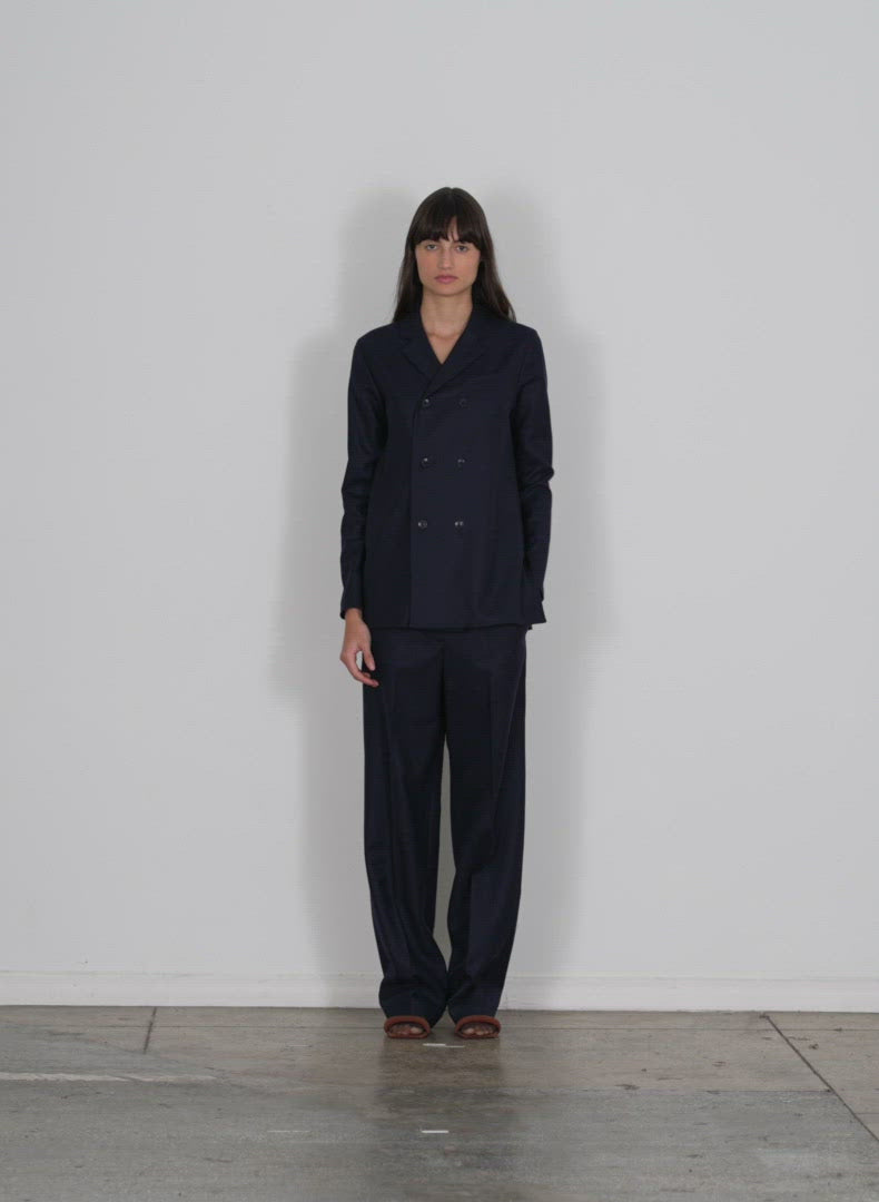 Model wearing the superfine wool flannel rodney straight leg trouser navy walking forward and turning around