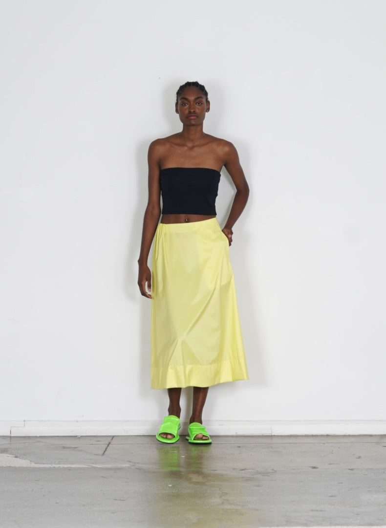 Model wearing the italian sporty nylon side shirred circle skirt yellow walking forward and turning around