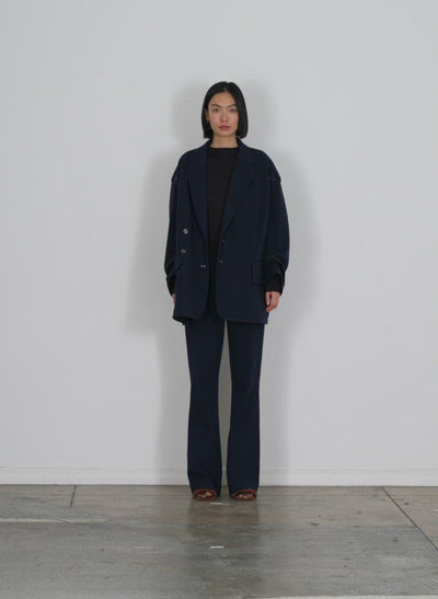 Model wearing the camille check ali fluid pant black navy multi walking forward and turning around