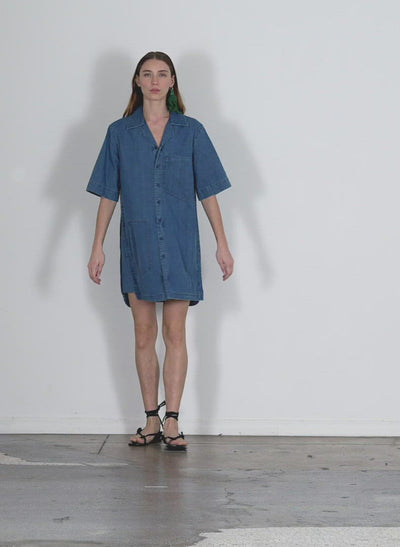 Model wearing the summer denim camp dress light denim walking forward and turning around