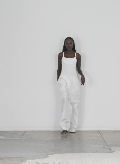 Model wearing the ribbed t racerback bodysuit white 1 walking forward and turning around