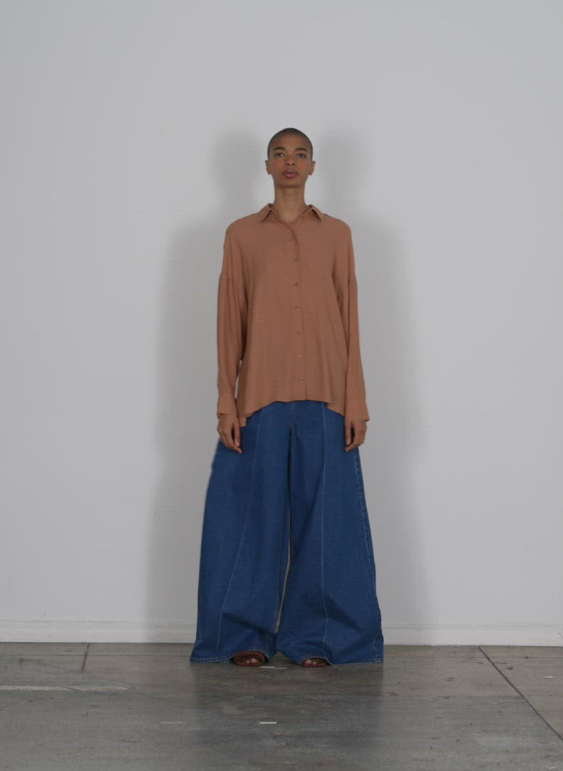 Model wearing the feather weight eco crepe oversized shirt sunset tan walking forward and turning around