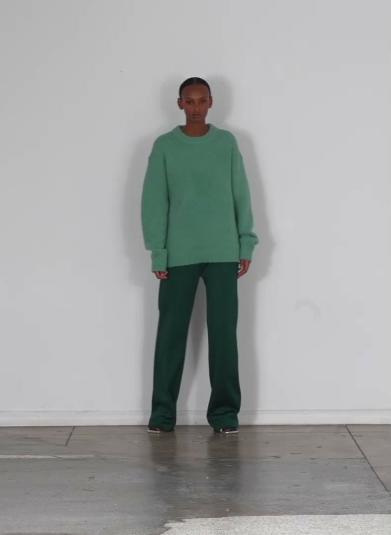 Model wearing the airy alpaca crewneck pullover fern green walking forward and turning around