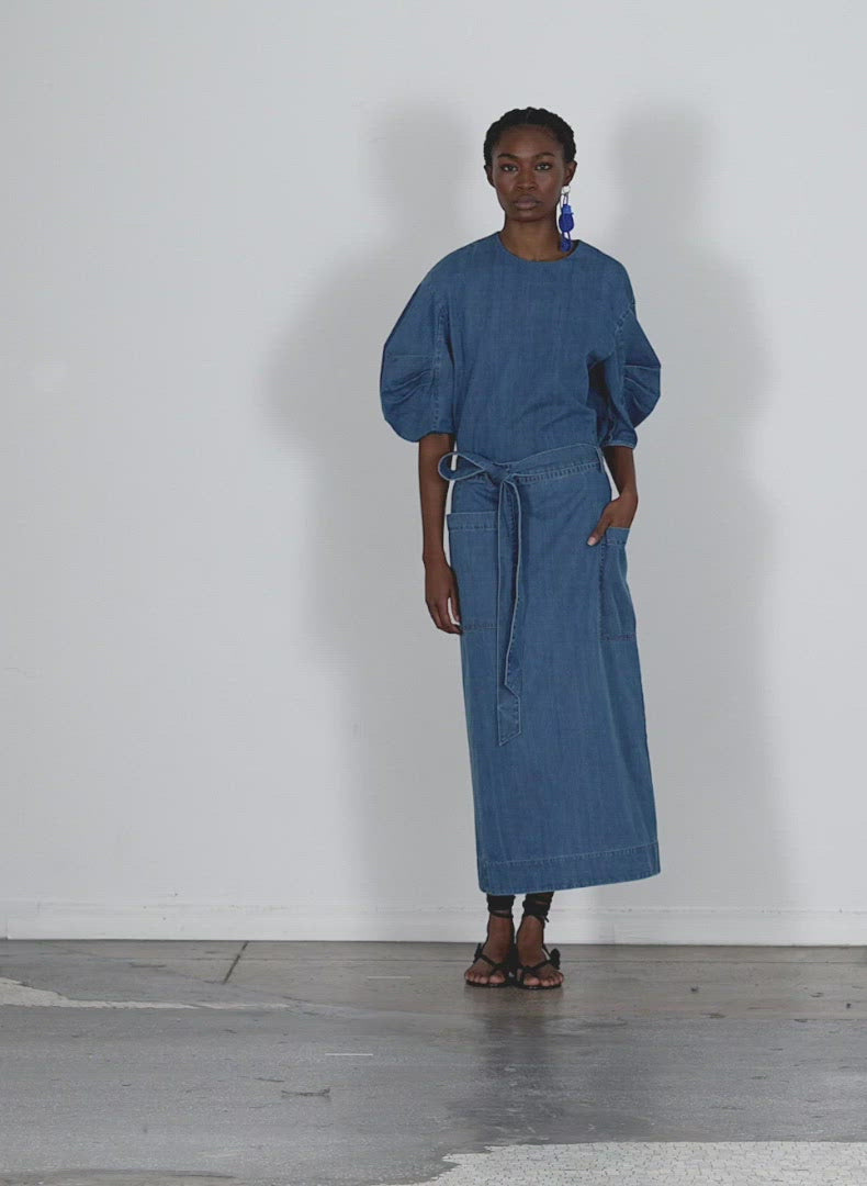 Model wearing the summer denim pleat sleeve top light denim walking forward and turning around