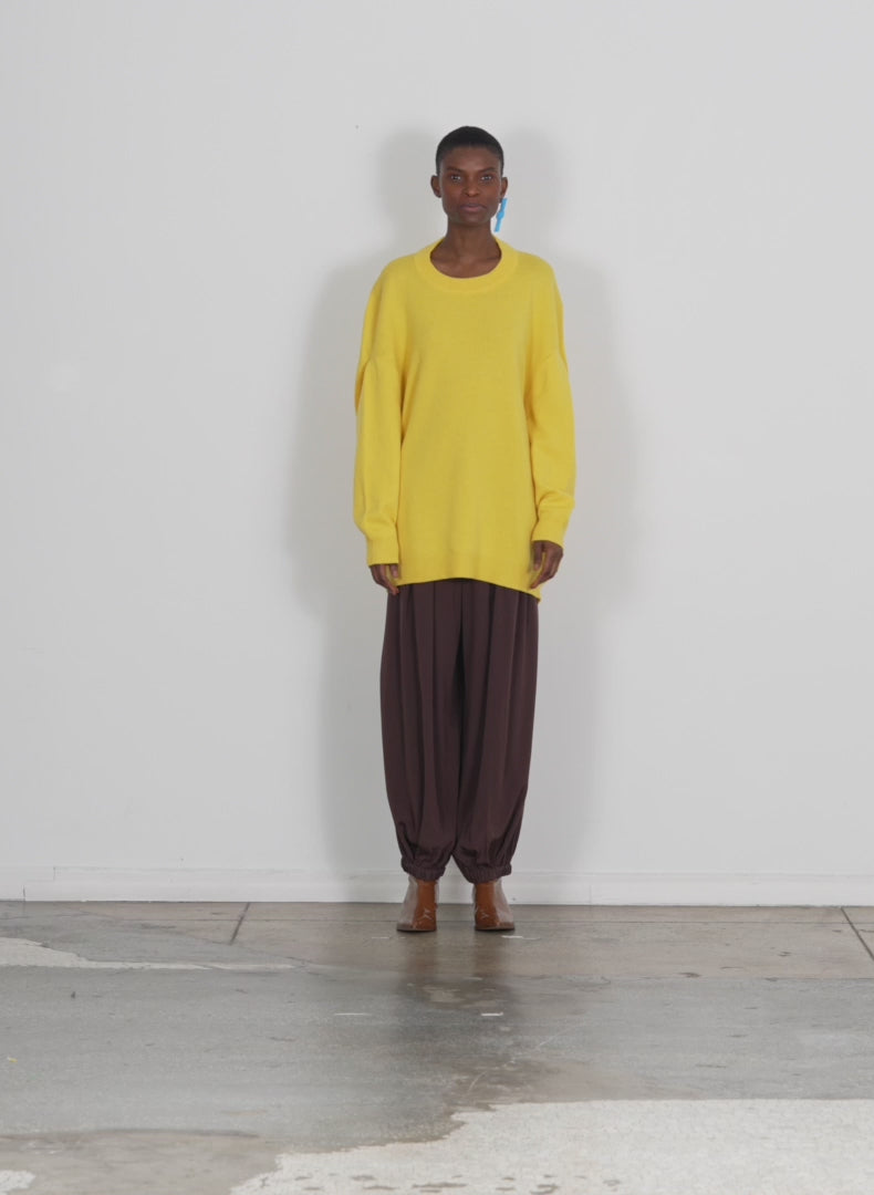 Model wearing the airy extrafine wool circular origami pullover yellow walking forward and turning around