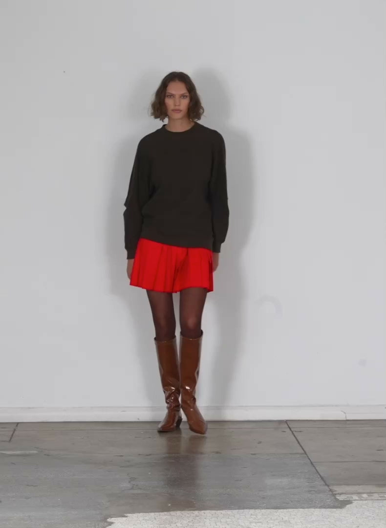 Model wearing the italian sporty nylon pleated pullon mini skirt red walking forward and turning around