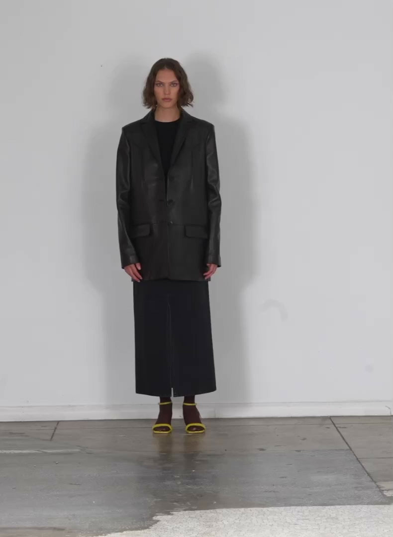 Model wearing the black denim petite maxi skirt black walking forward and turning around