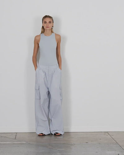 Model wearing the powder nylon pleated cargo pant blue grey walking forward and turning around