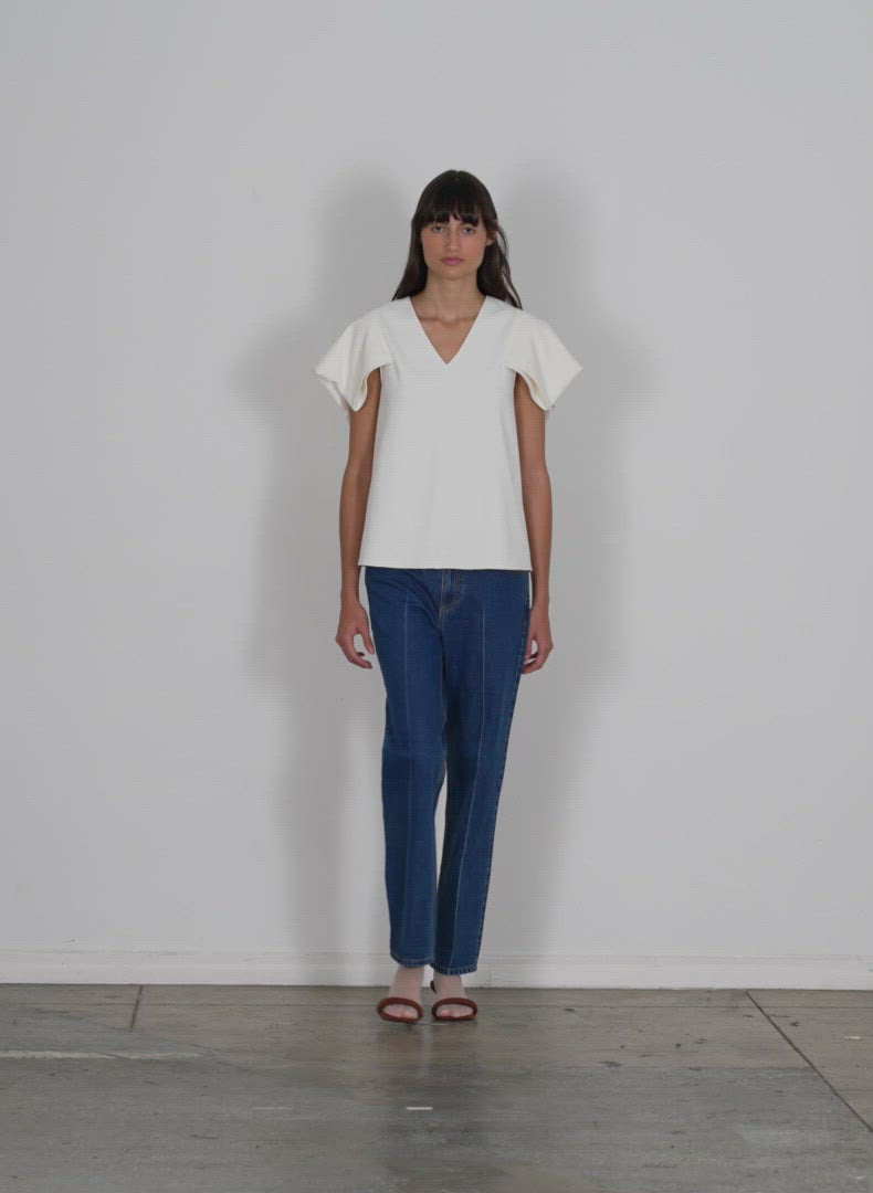 Model wearing the chalky drape vneck top with folded sleeve black walking forward and turning around