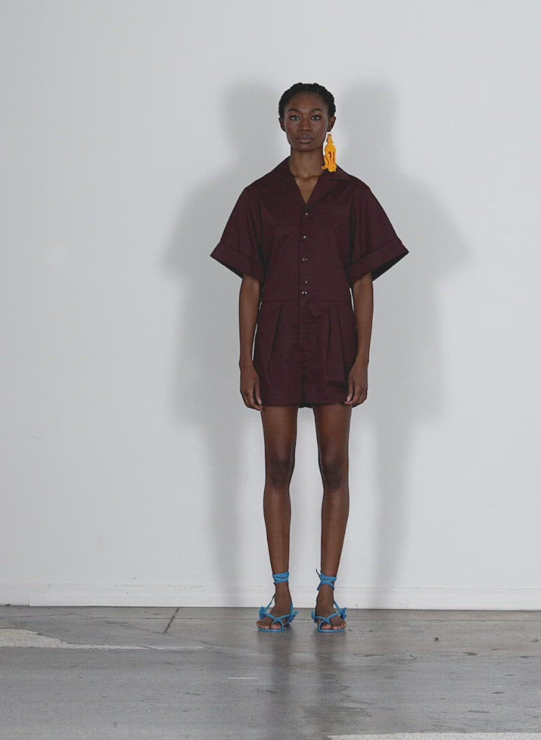 Model wearing the eco poplin short jumpsuit brown walking forward and turning around