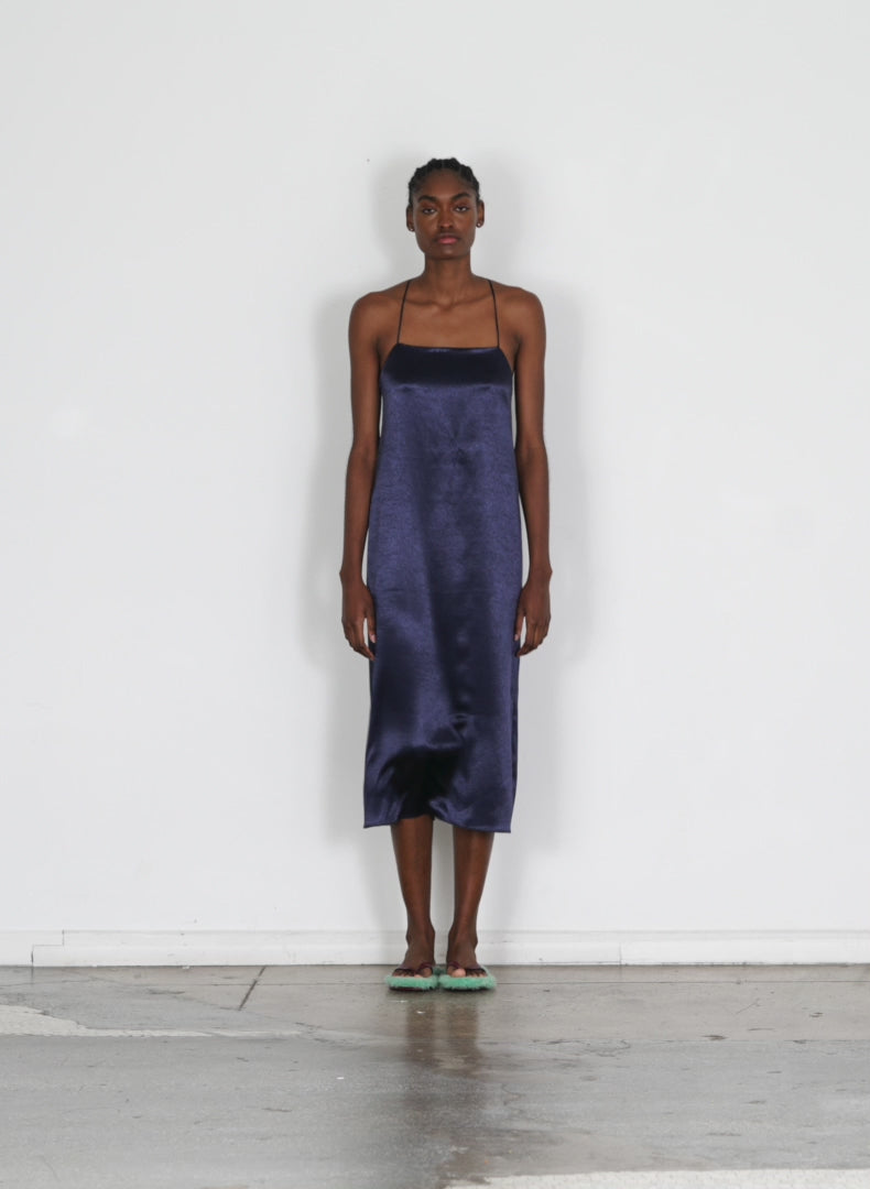 Model wearing the summer satin slip dress dark navy walking forward and turning around