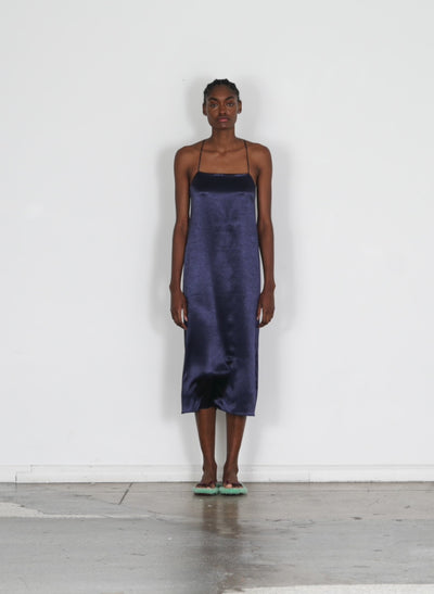 Model wearing the summer satin slip dress dark navy walking forward and turning around