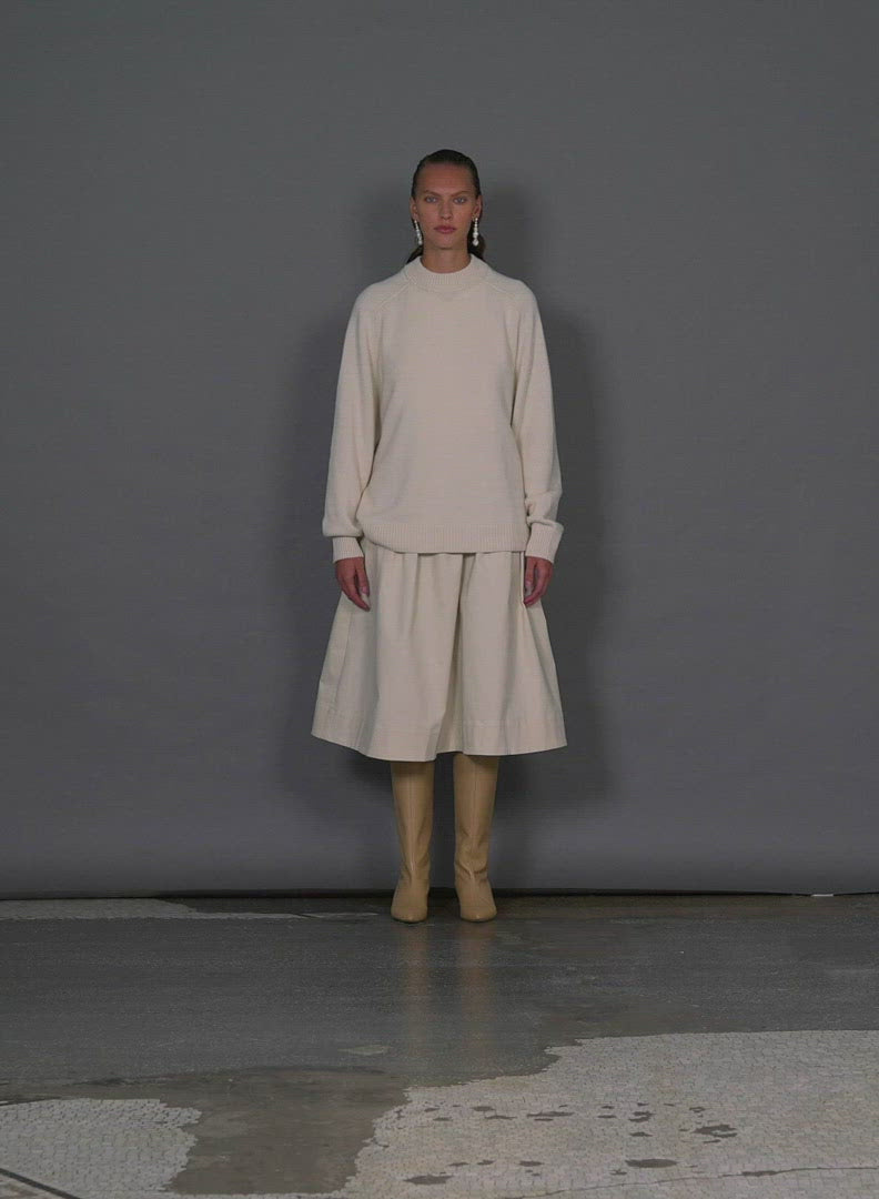 Model wearing the cashmere sweater crewneck oversized pullover ivory walking forward and turning around