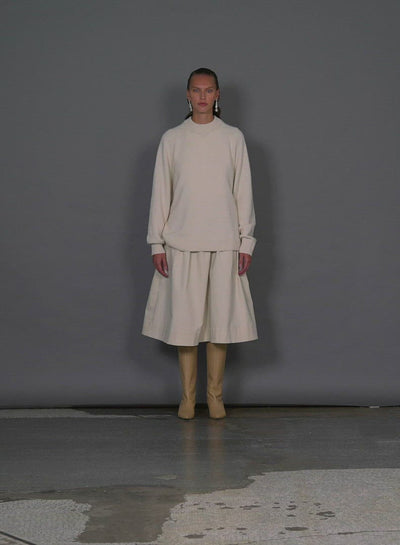 Model wearing the cashmere sweater crewneck oversized pullover ivory walking forward and turning around