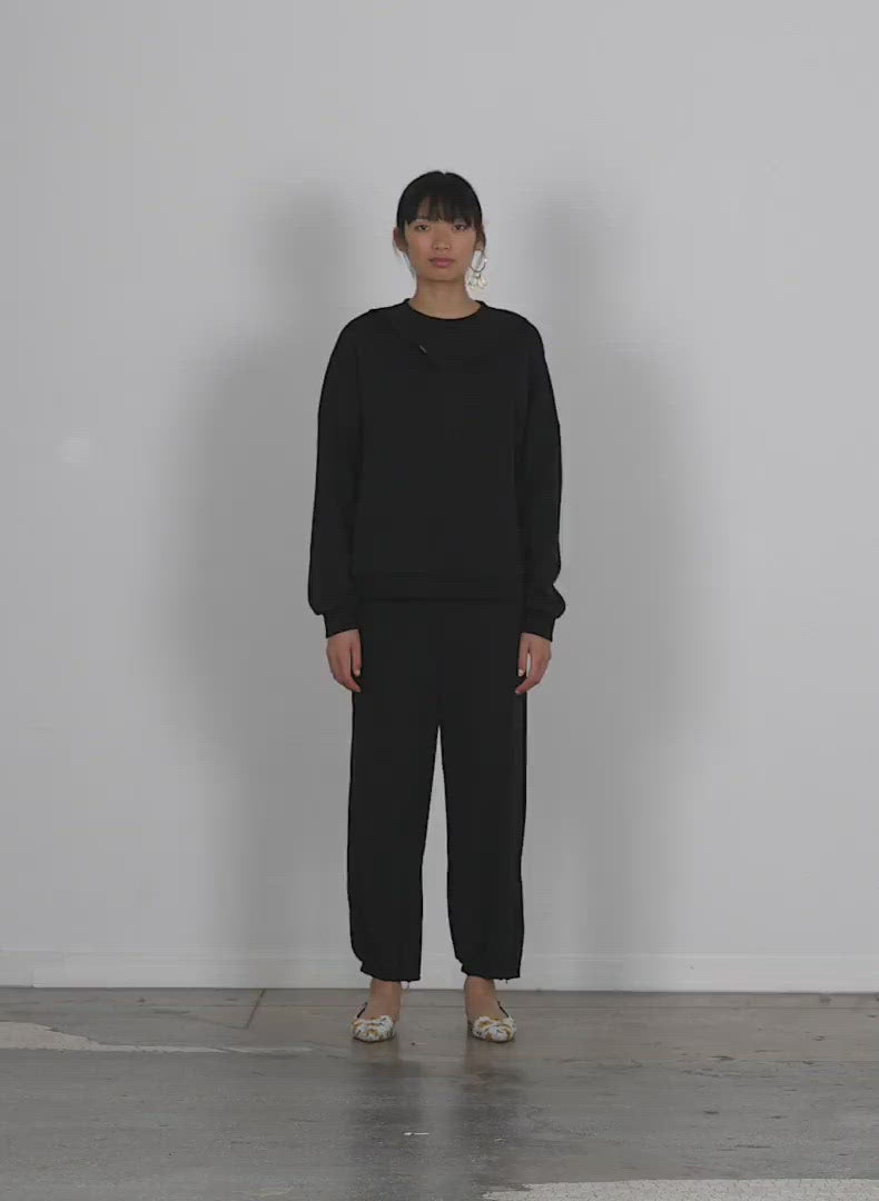Model wearing the cropped sweatpant w zip walking forward and turning around
