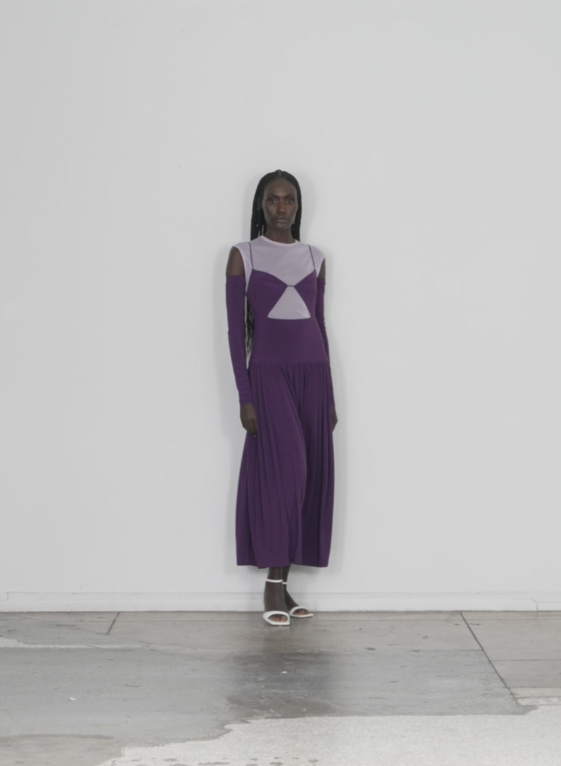 Model wearing the drapey jersey cut out sculpted shirred dress plum dusty lavender multi walking forward and turning around