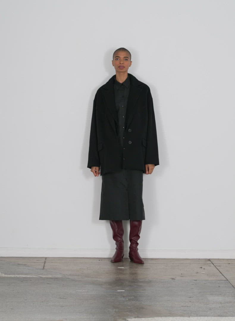 Model wearing the recycled wool cashmere dbl collar liam coat jacket black walking forward and turning around