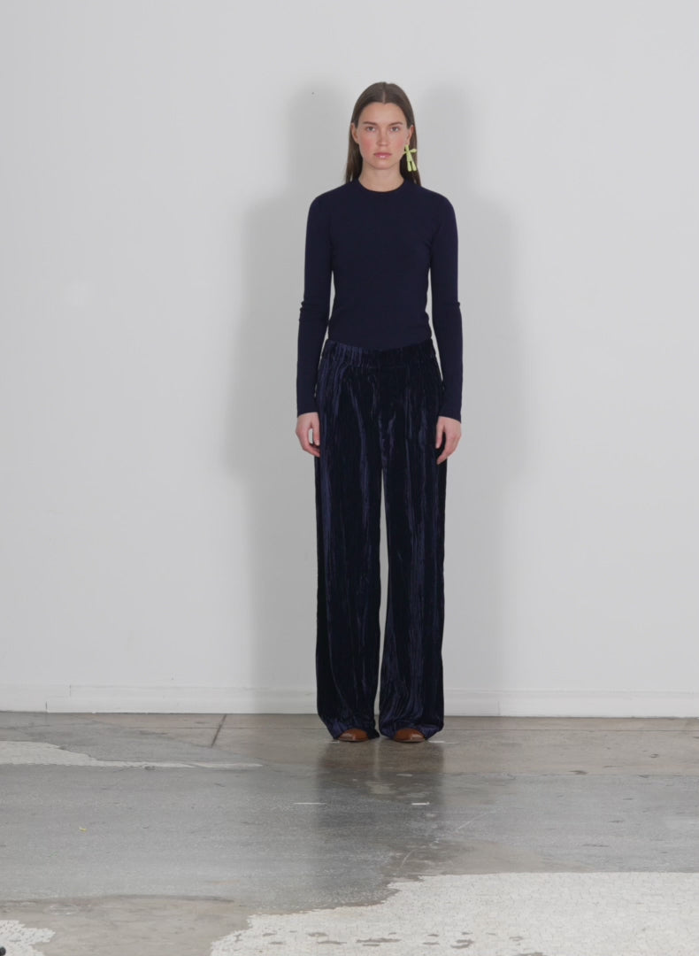 Model wearing the creased velvet stella pant navy walking forward and turning around