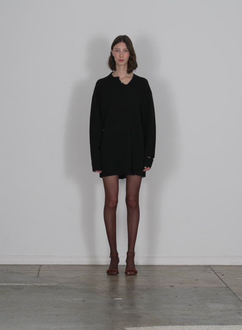 Model wearing the soft lambswool cutout neckband mini dress black walking forward and turning around