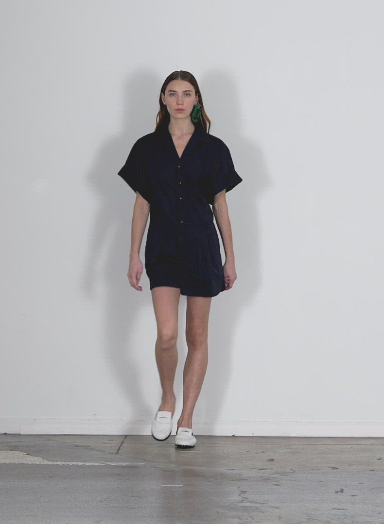 Model wearing the eco poplin short jumpsuit dark navy walking forward and turning around